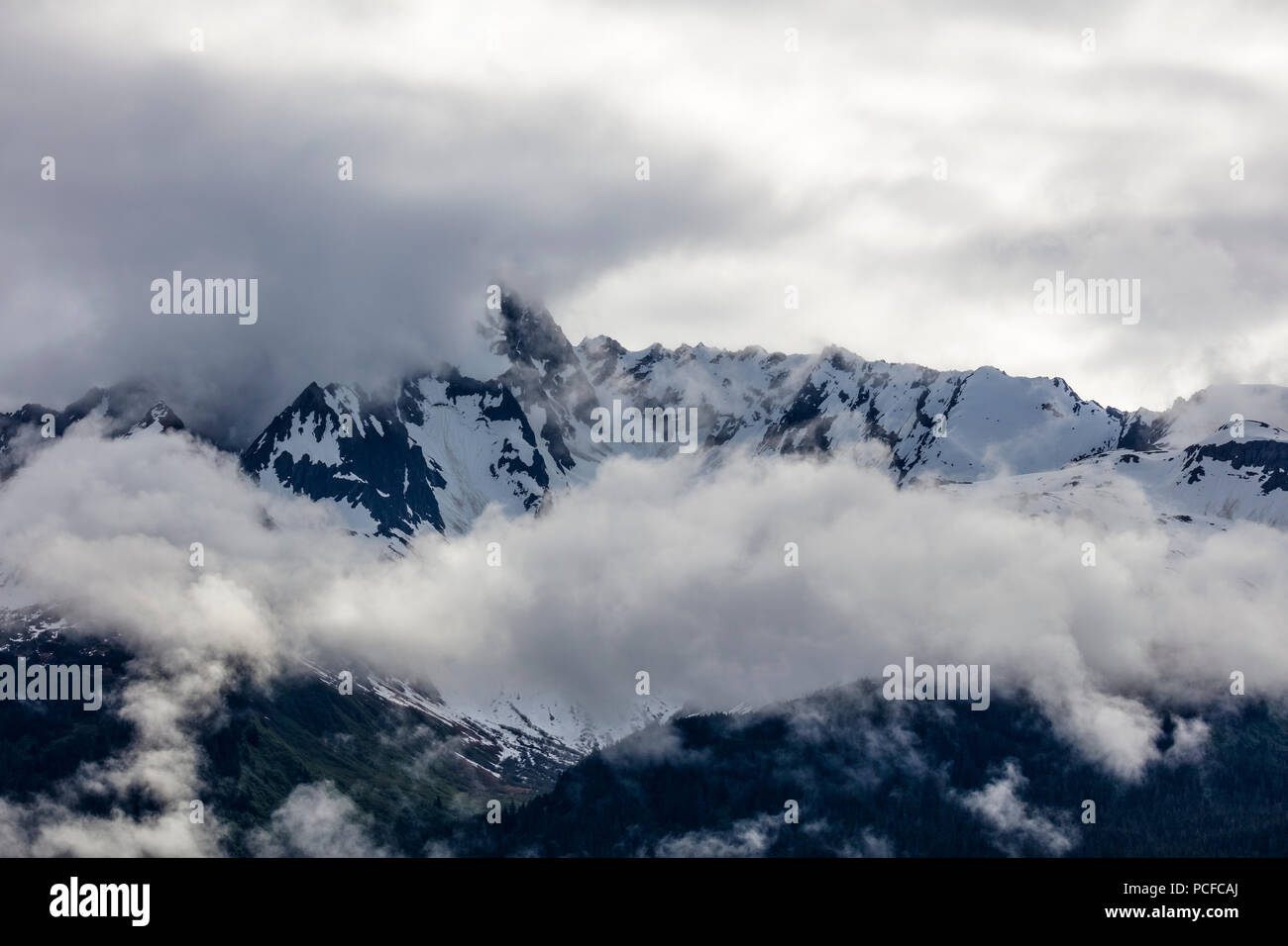 Snow capped rugged rocky mountains in clouds on the Kenai Peninsula of Alaska Stock Photo