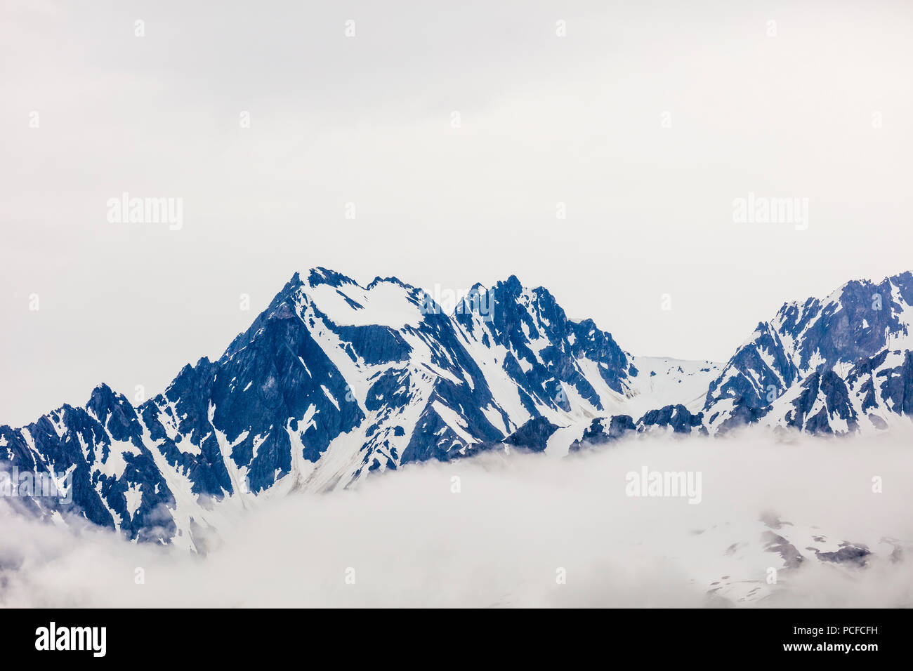 Snow capped rugged rocky mountains in clouds on the Kenai Peninsula of Alaska Stock Photo