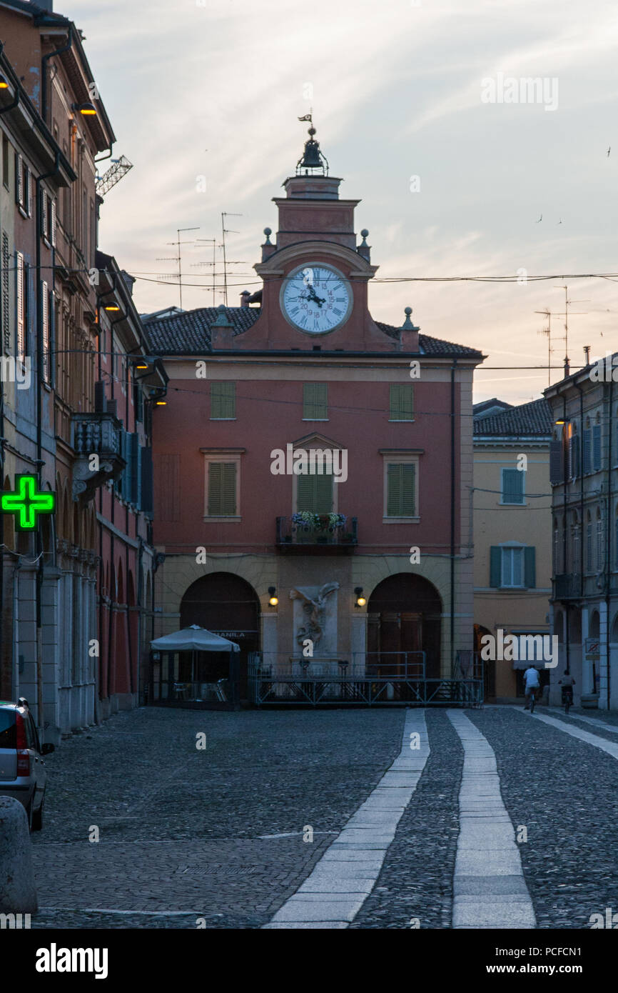 Clock tower and pharmacy sign of a street in a vintage town in Italy