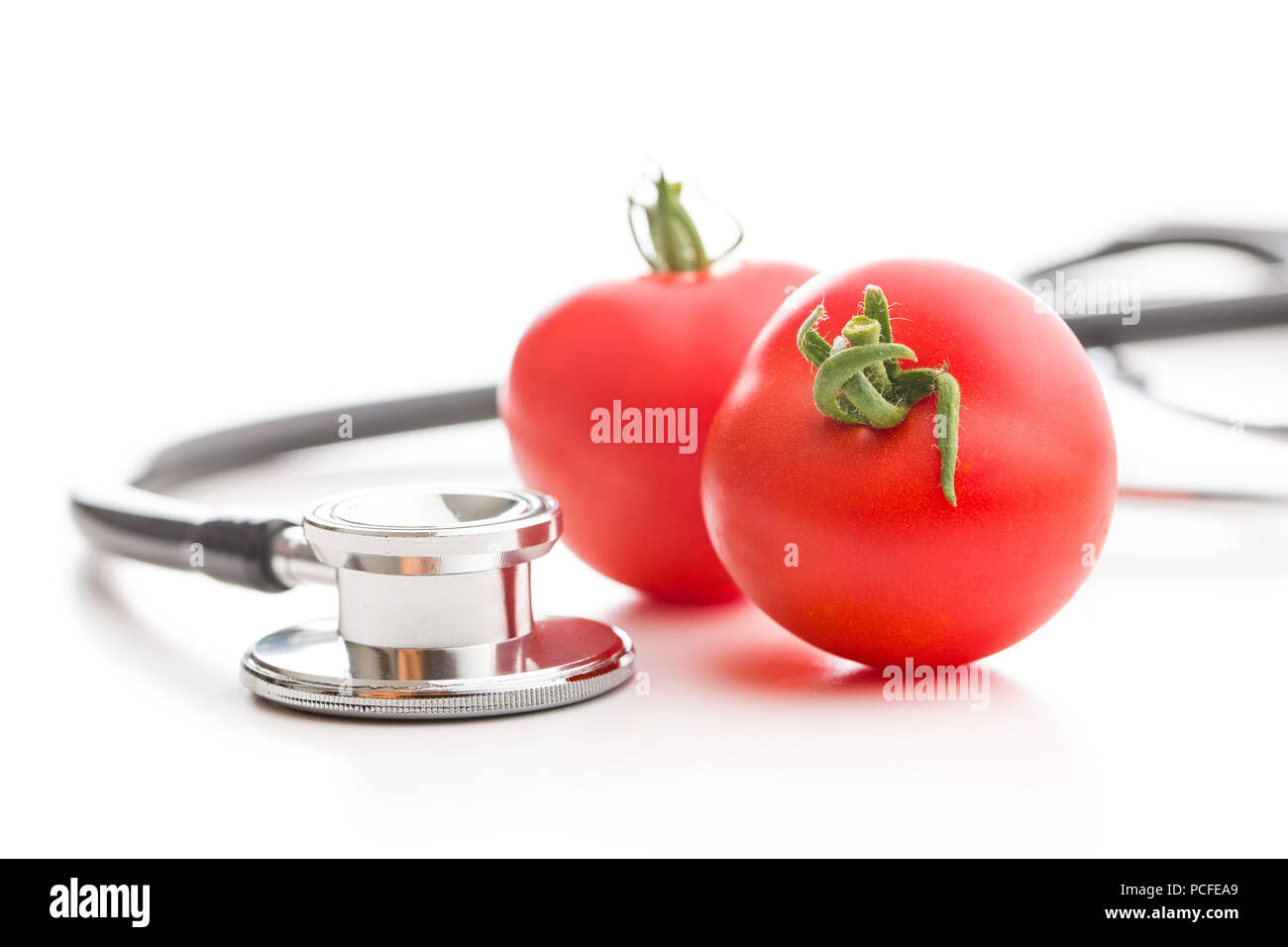 Red tomatoes and stethoscope isolated on white background. Stock Photo