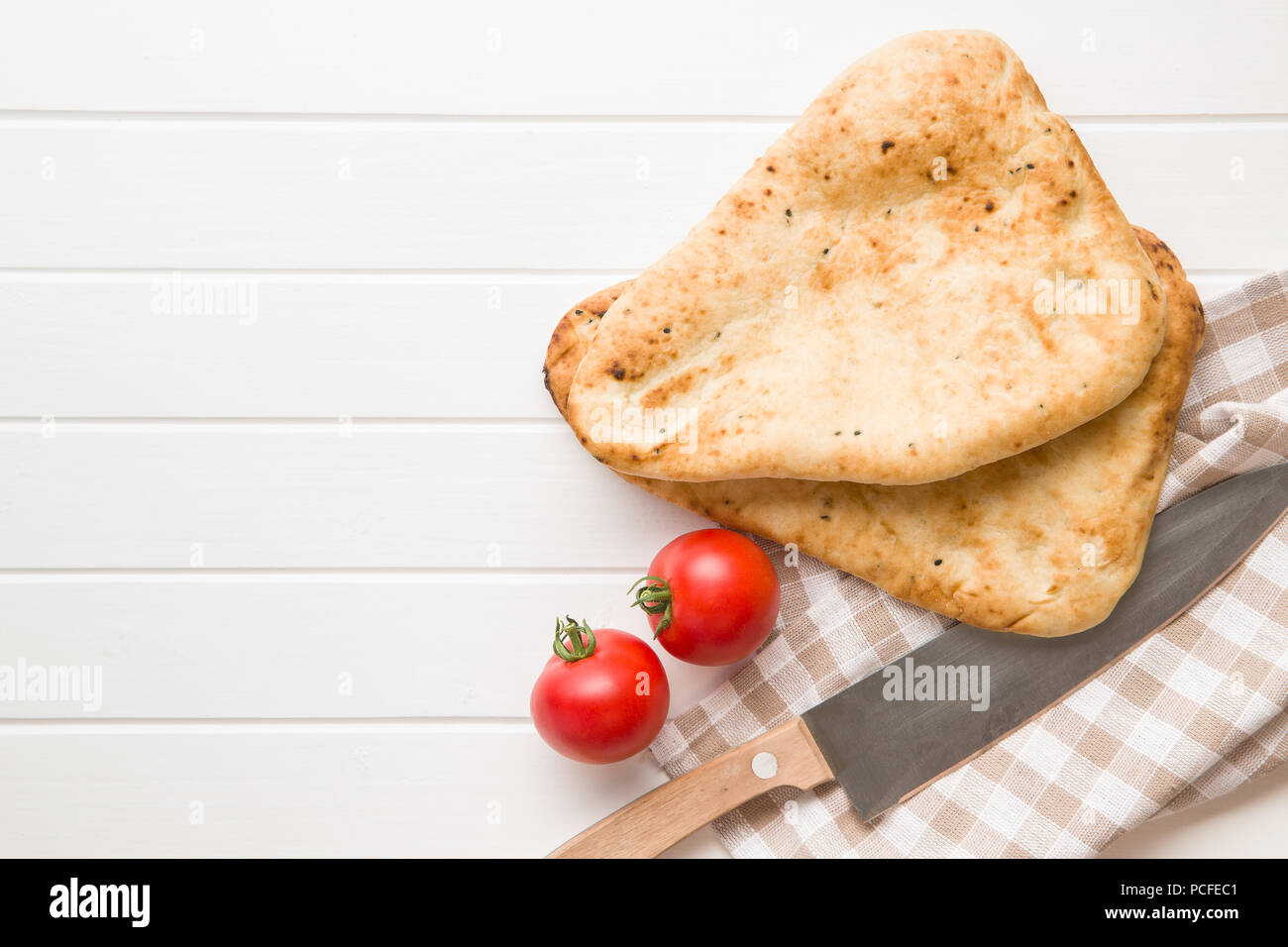 Indian naan bread and tomatoes on white kitchen table. Stock Photo