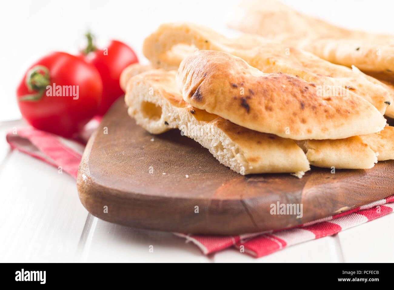 Indian naan bread and tomatoes on white kitchen table. Stock Photo