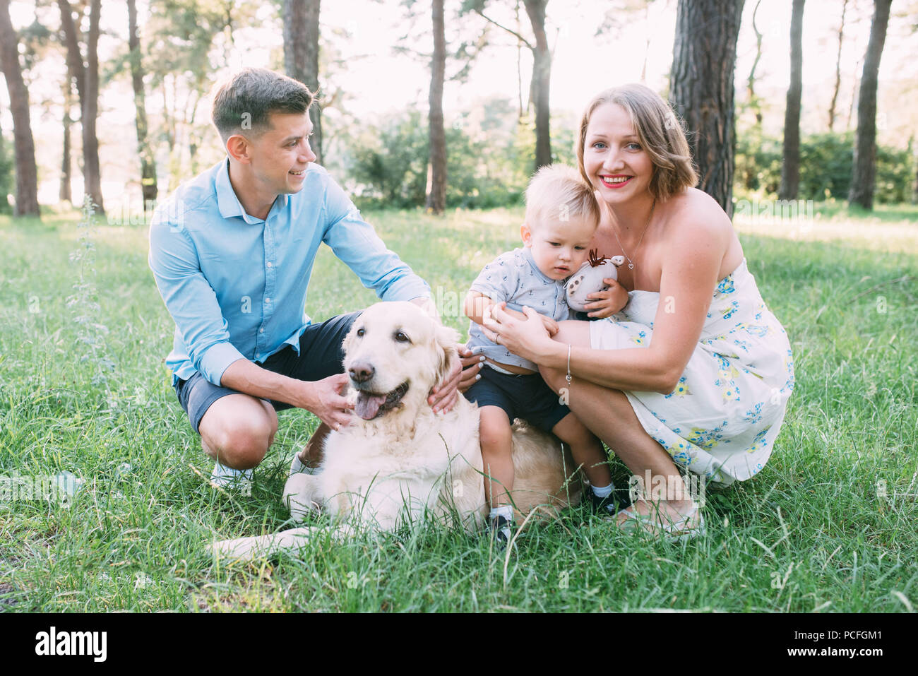 A cute family - mom, dad and son spend fun time outdoors with their dog ...