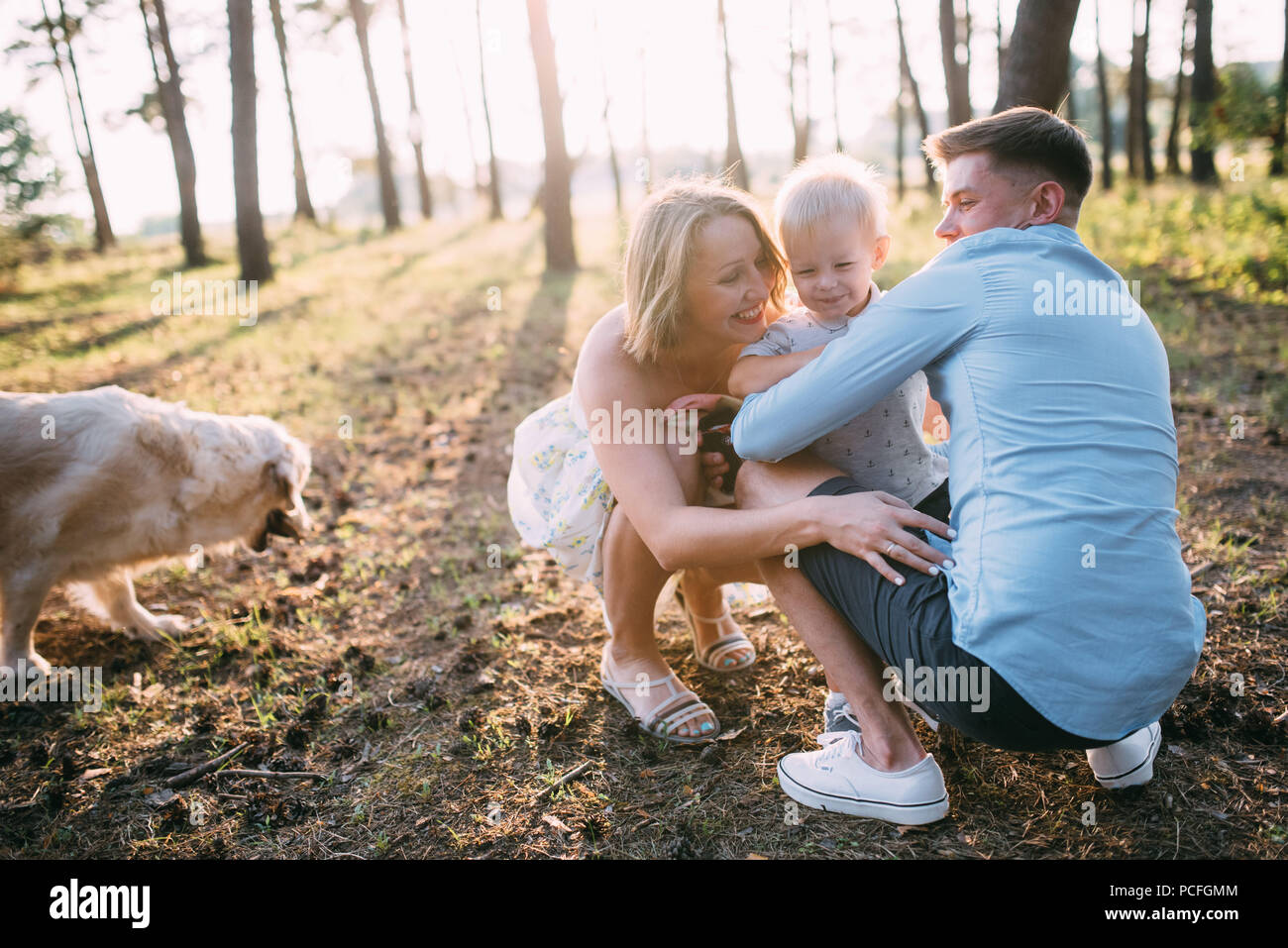 A cute family - mom, dad and son spend fun time outdoors with their dog ...