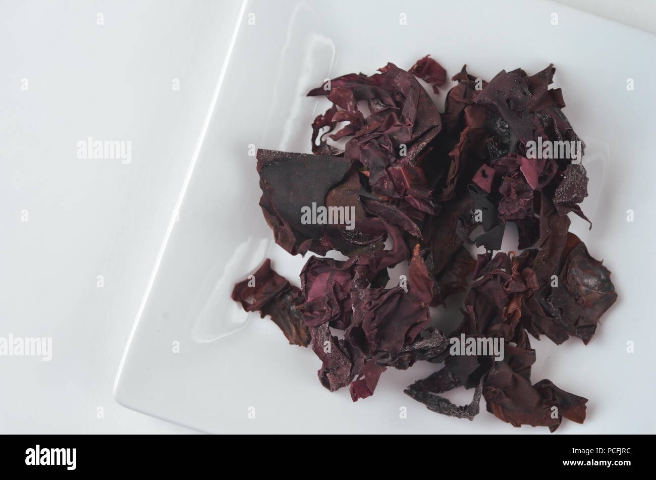 Detail top view of dried seaweed:  dulse (Palmaria palmata). Isolated on white.Nutrient rich vegan, raw and healthy sea vegetables. Stock Photo