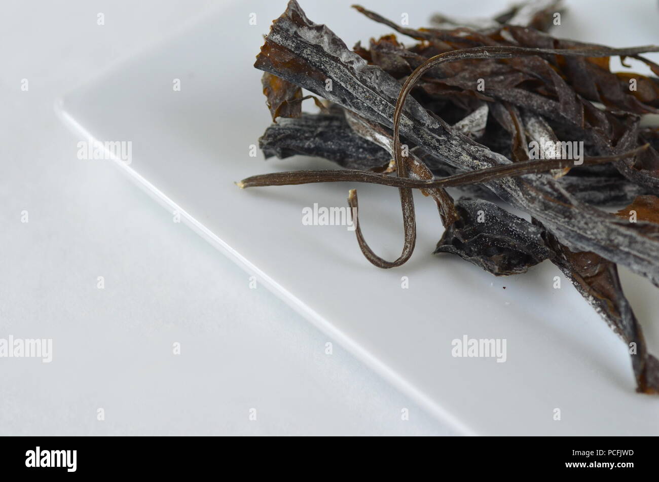 Detail top view of dried seaweed:  wakame. Isolated on white.Nutrient rich vegan, raw and healthy sea vegetables. Stock Photo
