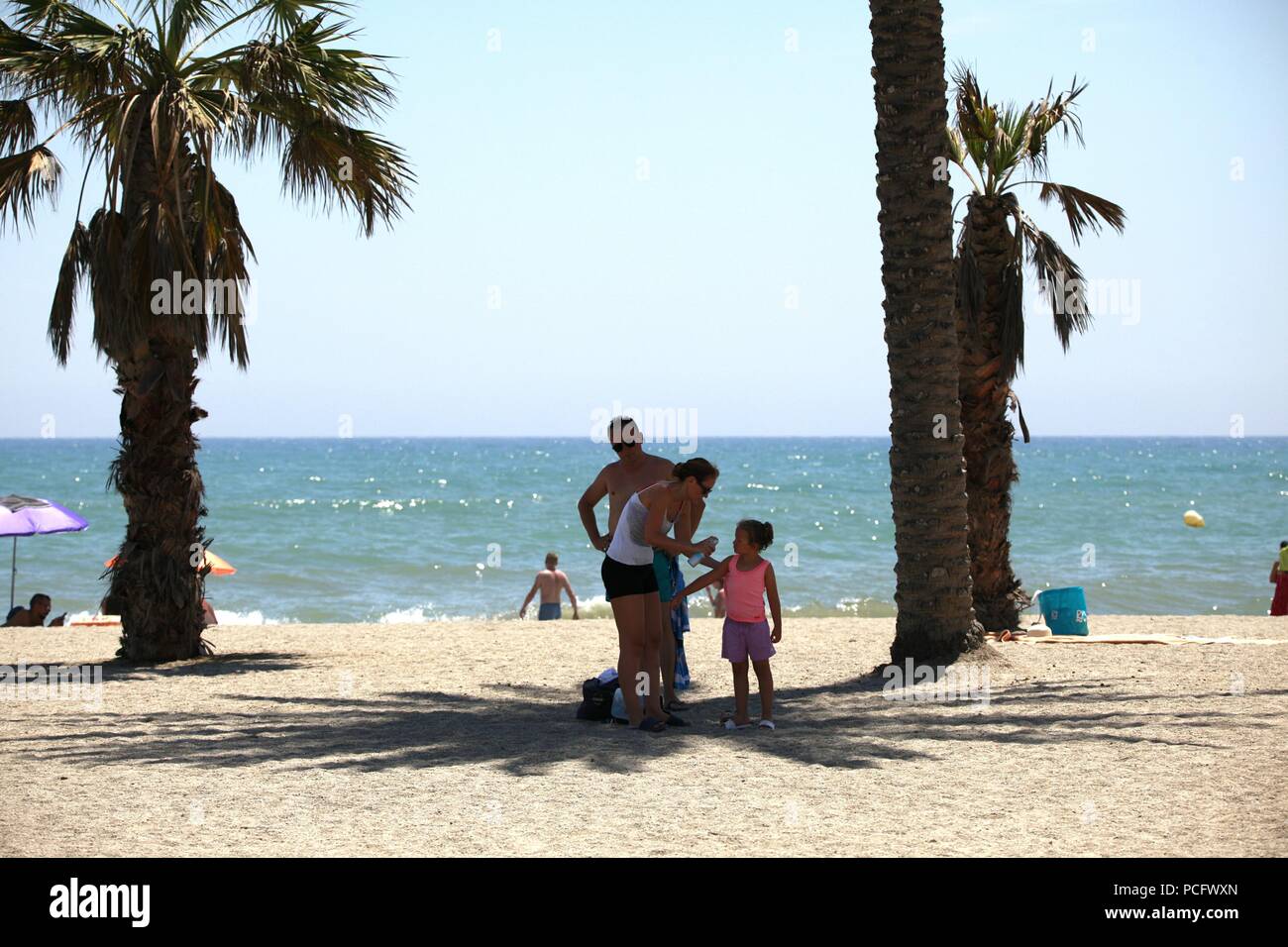 Roquetas de Mar, Almeria, Spain. 2nd Aug, 2018. The heatwave that is hitting Spain is expected to exceed 43Â°C in some parts of the country. Roquetas de Mar is a small tourist town west of the capital city of Almeria, famed for its Moorish castle. A family stands under the shade of a palm tree on the beach with the mediteranian sea in the background. Photo Credit: Paul Lawrenson /Alamy Live News Stock Photo