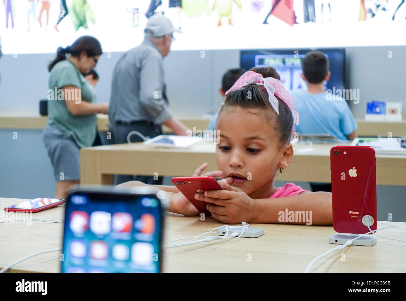New York, USA. 2nd Aug, 2018. A girl tries a product at an Apple store in New York, the United States, Aug. 2, 2018. U.S. tech giant Apple became the first American company that saw its market cap hit 1 trillion U.S. dollars in the U.S. history after its shares rose 2.8 percent to a session high of 207.05 dollars around midday trading on Thursday. Credit: Wang Ying/Xinhua/Alamy Live News Stock Photo