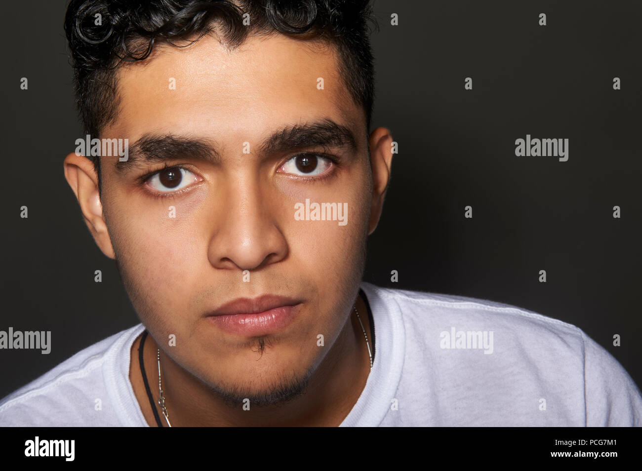 Studio portrait of a 19 years old young man, wearing a white t-shirt, looking to the camera Stock Photo