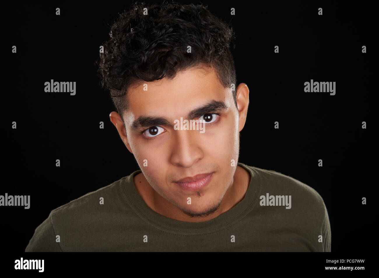 Studio portrait of a 19 years old friendly young man, wearing an olive t-shirt, looking to the camera Stock Photo