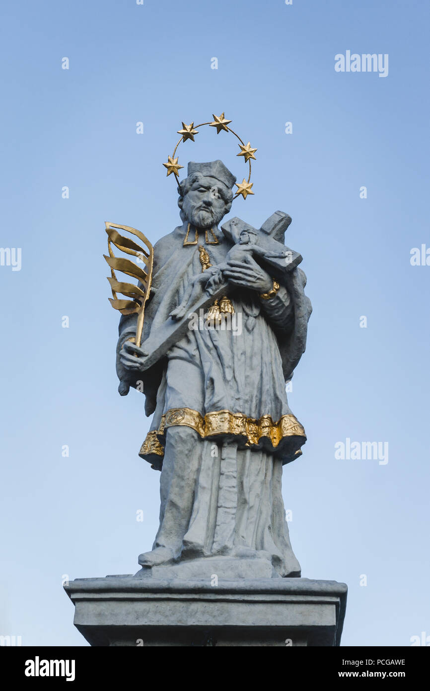 Statue of Saint John of Nepomuk in Olesno, Poland with gold elements, palm of martyrdom, halo of five stars, robes and crucifix cross with Jesus. Stock Photo
