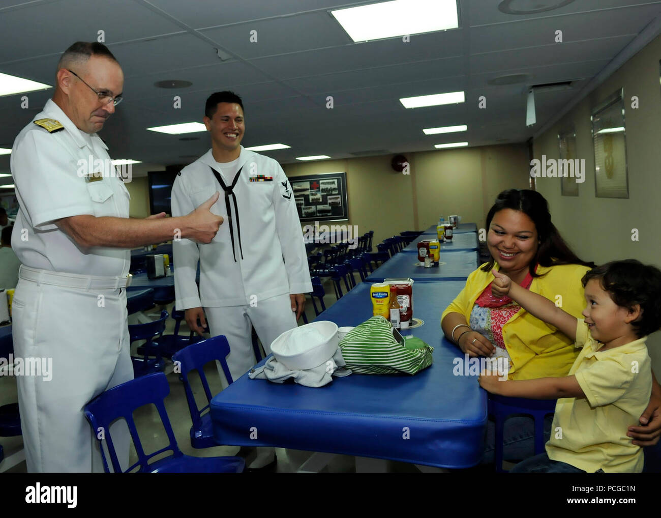 Rear Adm. C. Forrest Faison III, commander of Navy Medicine West, gives a thumbs-up to a boy and his parents in the mess decks aboard the Military Sealift Command hospital ship USNS Mercy (T-AH 19). Nearly 500 medical and support staff from Navy Medicine West are deployed aboard Mercy supporting Pacific Partnership 2012. Pacific Partnership is an annual U.S. Pacific Fleet humanitarian and civic action exercise designed to work with and through host nations to build partnerships and a collective ability to respond to natural disasters. Stock Photo