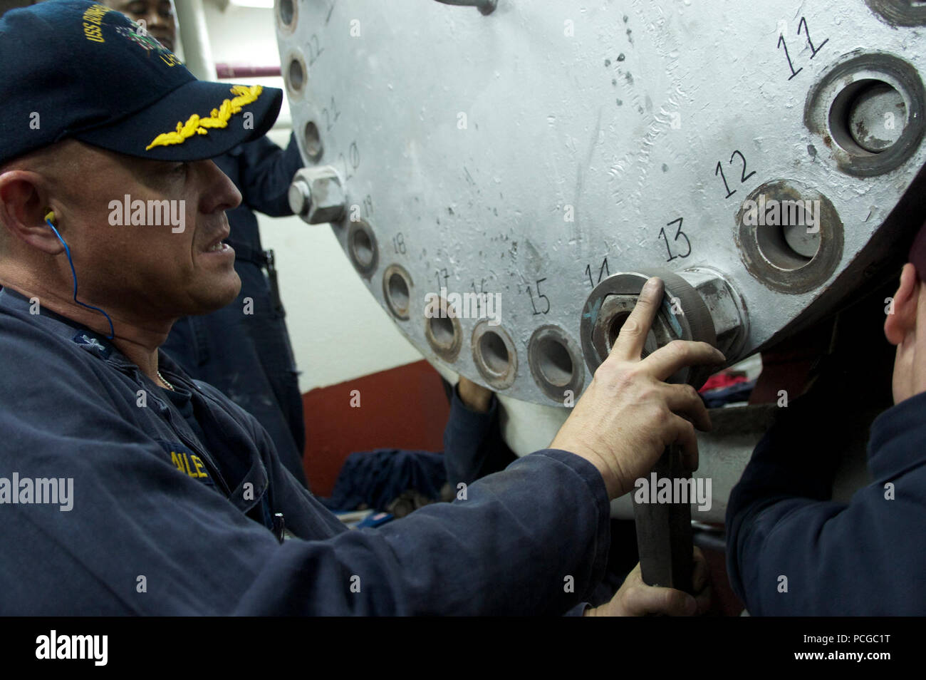 Cmdr. Robert Bailey, chief engineer aboard the amphibious assault ship USS Bonhomme Richard (LHD 6), removes a bolt during repairs to one of the ship's boilers during a port call in Okinawa, Japan. The ship is en route to relieve USS Essex (LHD 2) in Sasebo, Japan. Stock Photo