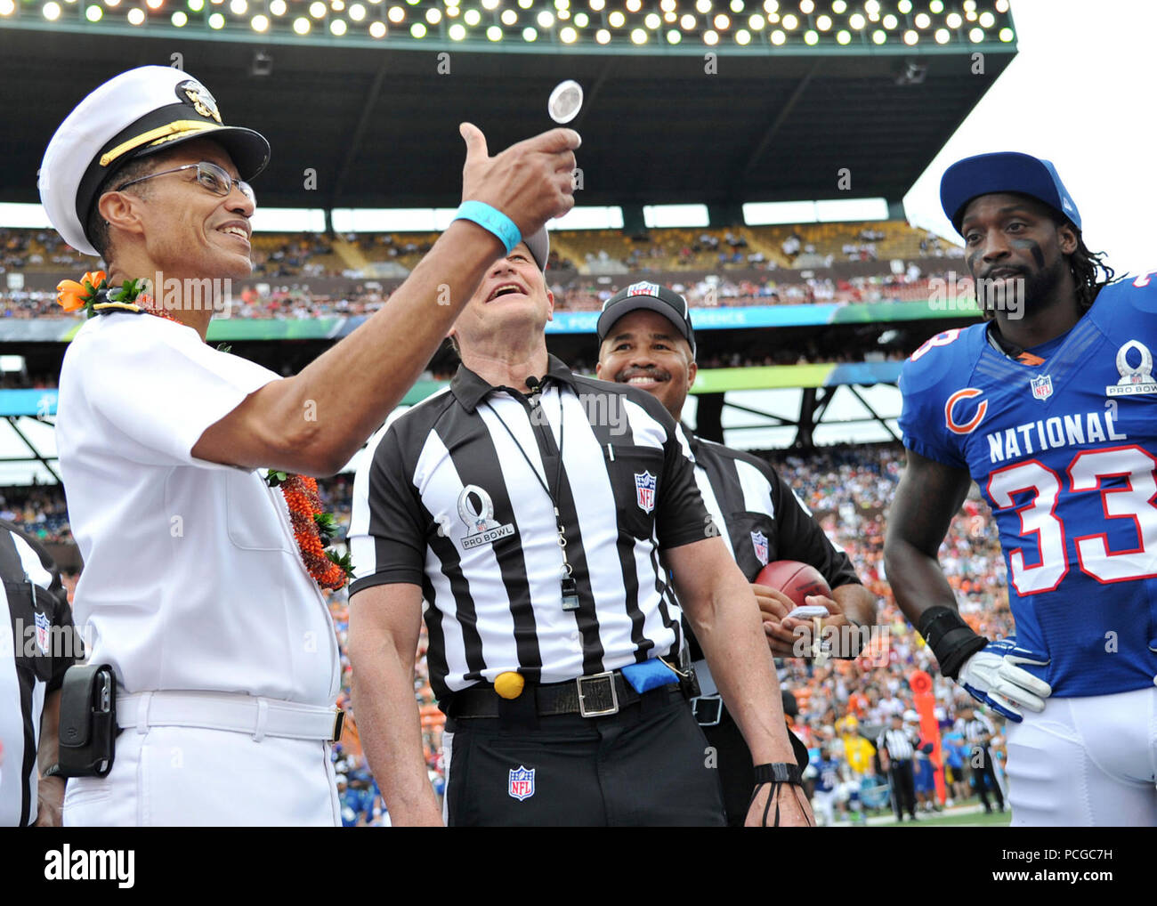 HONOLULU (Jan. 27, 2013) Adm. Cecil Haney, commander of U.S. Pacific Fleet, flips the ceremonial coin to start the 2013 Pro Bowl as head referee Ed Hochuli and Chicago Bears cornerback Charles Tillman look on. Stock Photo
