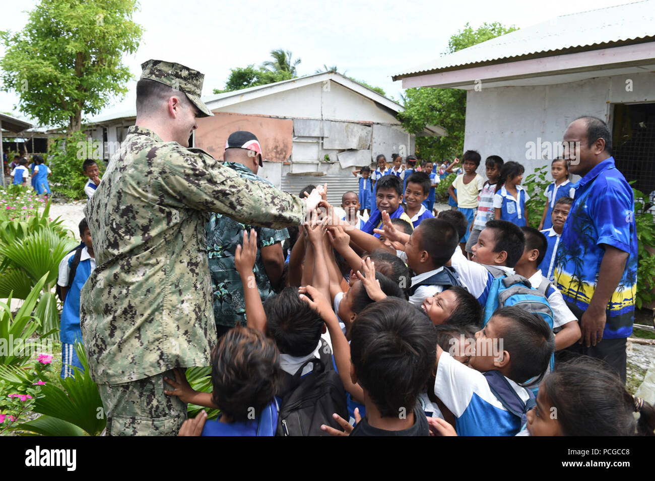 TARAWA, Kiribati (May 19, 2015) Advanced party engineer Lt. j.g. William Lindahl high fives students at the Bikenibeu West Primary School while surveying a future construction site for Pacific Partnership 2015. Pacific Partnership is in its 10th iteration and is the largest annual multilateral humanitarian assistance and disaster relief preparedness mission conducted in the Indo-Asia-Pacific region. While training for crisis conditions, Pacific Partnership missions to date have provided real-world medical care to approximately 270,000 patients and veterinary services to more than 38,000 animal Stock Photo
