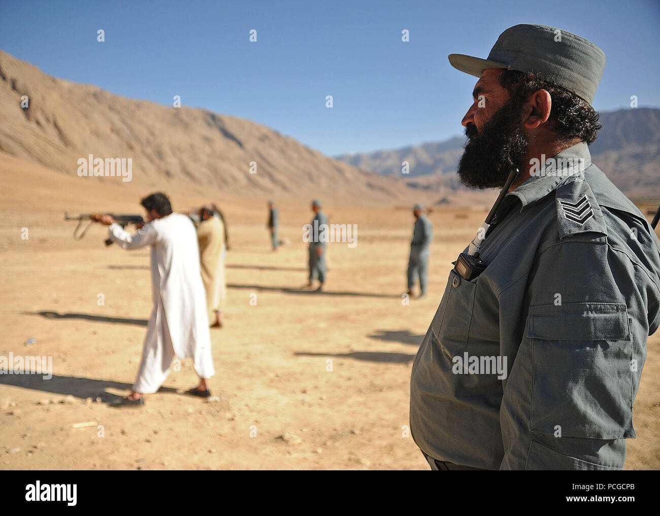 An Afghan Local Police instructor monitors ALP candidates as they fire their AK-47 rifles during weapons training in Gizab district, Uruzgan province, Afghanistan, Dec. 8. ALP provide village stability and police the area. Stock Photo