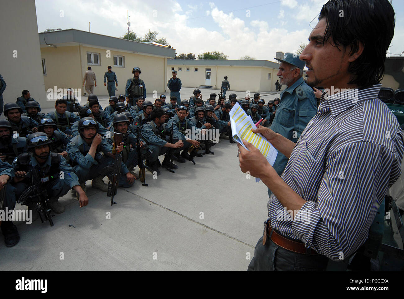 KABUL, Afghanistan (April 18, 2010) – Afghan translator Esmatullah Ebrahimkhail, right,  calls names of members of the Afghan National Civil Order Police (ANCOP), at a Kabul facility.  The police officers registered and received briefings and training as they prepare for operations in Afghanistan. (US Navy Stock Photo