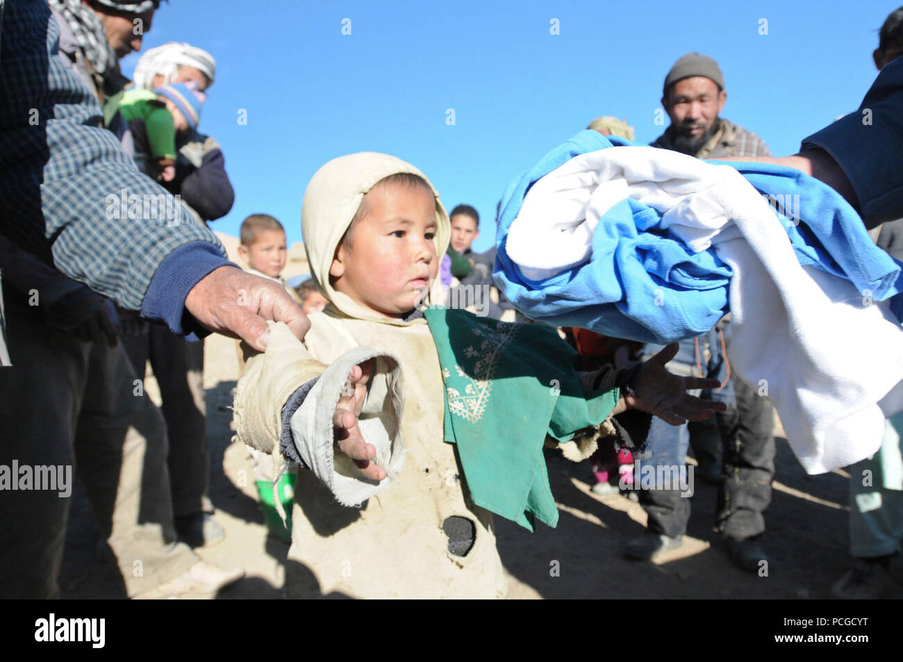 A young boy reaches for some warm clothes at Aq Robat, a remote village more than 20 miles northwest of Bamyan, Dec. 24. The clothes were donated by Operation Care: Afghanistan, a non-profit, private charitable organization based at Bagram Airfield, Afghanistan. Stock Photo