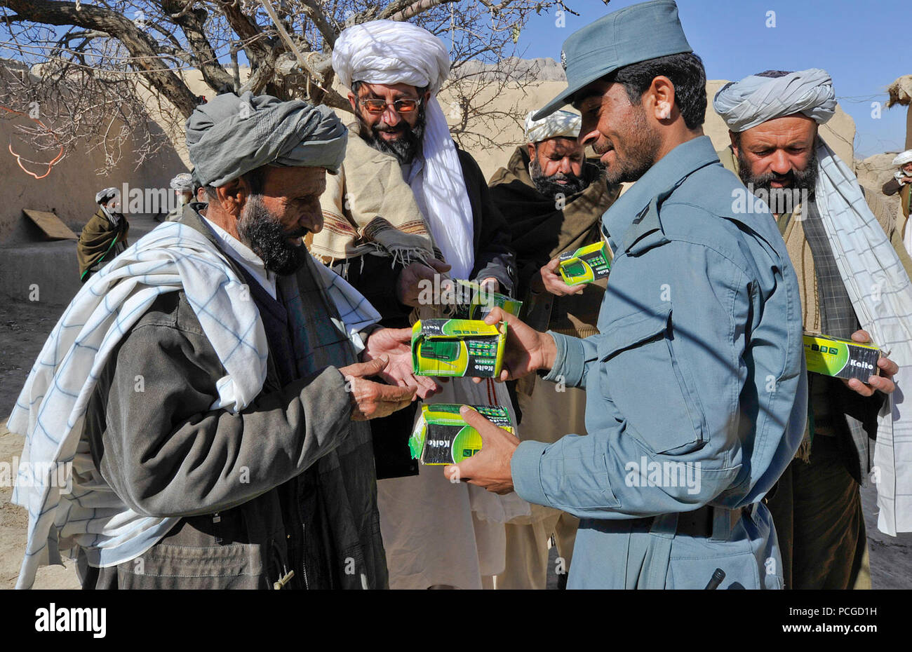 Afghan Uniformed Police distribute workbooks and radios to village elders in Walan Rabat, Zabul province, Afghanistan, Dec. 31. The items enable village children to participate in a locally broadcasted radio literacy program. Stock Photo