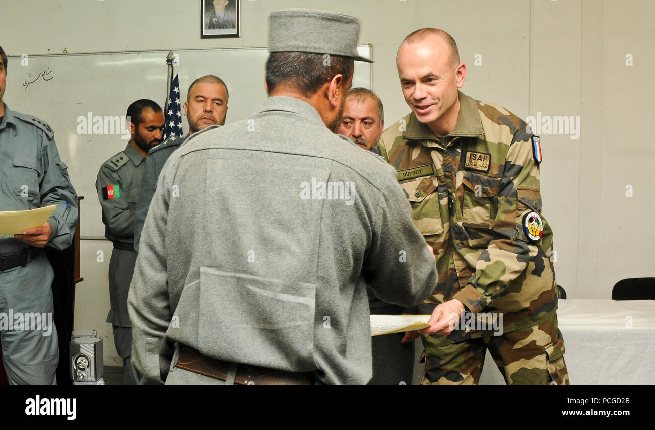 Brig. Gen. Christian Dupouy, deputy commander, NATO Training Mission-Afghanistan Deputy Command-Police, gives a certificate of completion to an Afghan National Police (ANP) trainee who graduated from the Afghanistan Human Resources Information Management System (AHRIMS) course at the Central Training Center (CTC), March 19, 2013. During this 21-day course, ANP learned the database, navigation, scanning and loading process to better the method of filing personal medical, training and promotion records during individuals' career paths to help eliminate the physical paper upkeep toward a computer Stock Photo