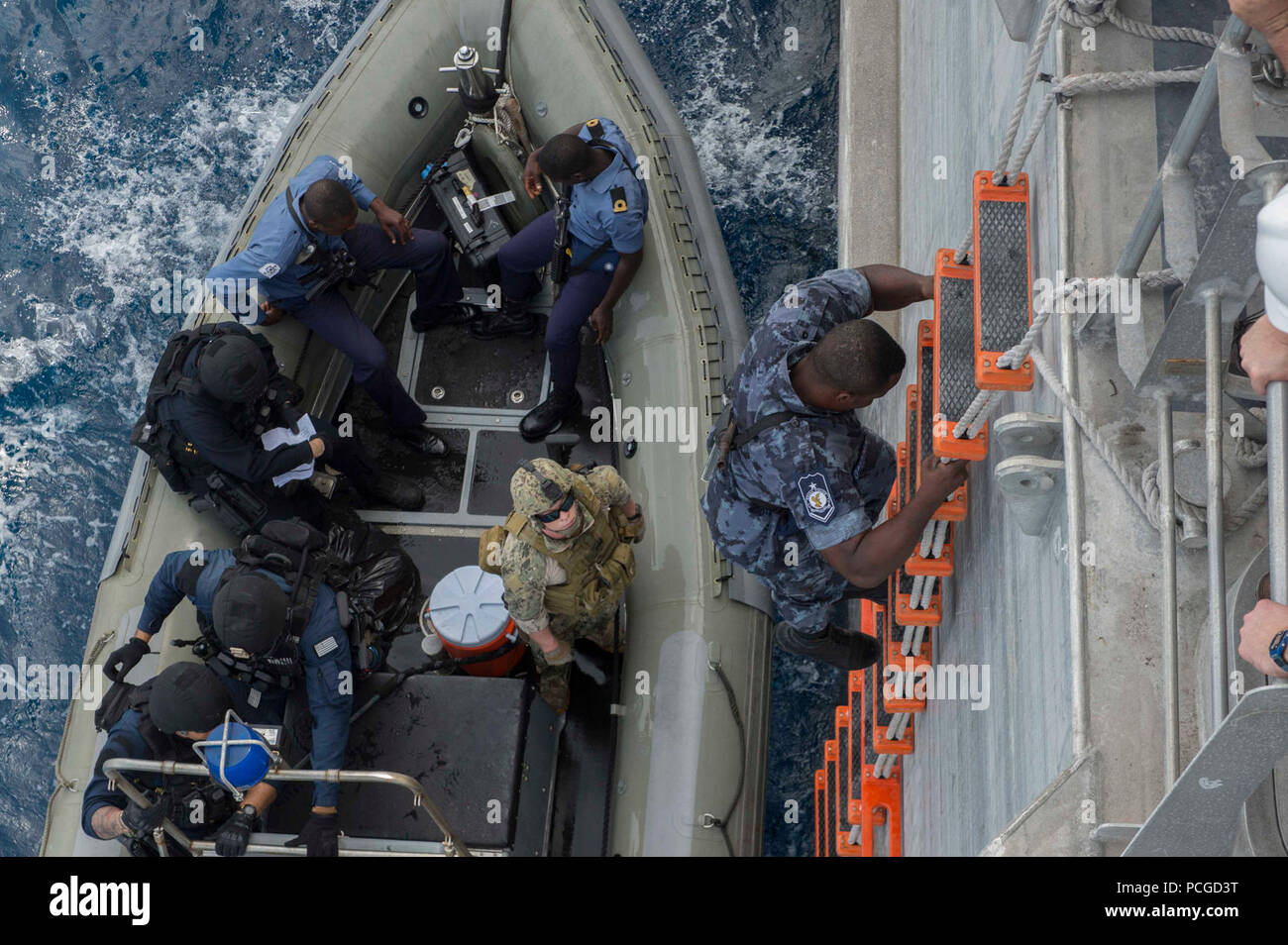OF GUINEA (March 26, 2014) A Ghanaian sailor embarked aboard the Military Sealift Command joint high-speed vessel USNS Spearhead (JHSV 1) climbs down into the rigid-hull inflatable boat during small boat operations as part of a U.S. and Ghana navy combined maritime law enforcement operation under the African Maritime Law Enforcement Partnership  program. Stock Photo