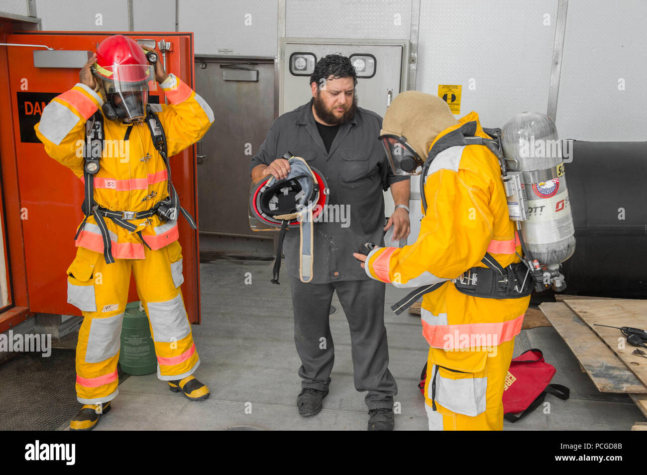 GULF OF GUINEA (March 24, 2015) Civil service mariners dress out during a fire drill in the mission bay of the Military Sealift Command’s joint high-speed vessel USNS Spearhead (JHSV 1) March 24, 2015. Spearhead is on a scheduled deployment to the U.S. 6th Fleet area of operations to support the international collaborative capacity-building program Africa Partnership Station. Stock Photo