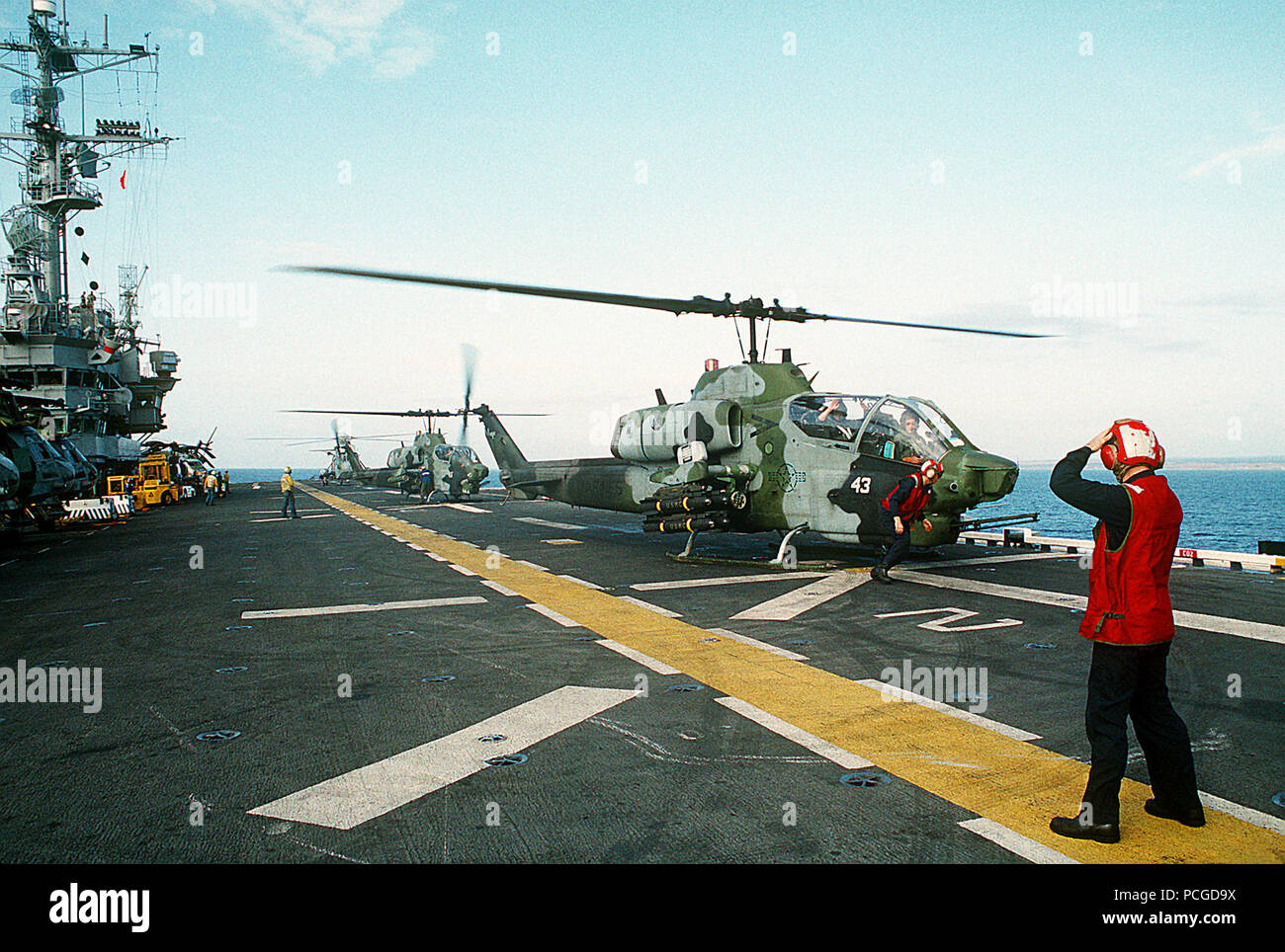 A pair of Marine Medium Helicopter Squadron 164 (HMM-164) AH-1W Sea Cobra helicopters prepare to takeoff from the amphibious assault ship USS TRIPOLI (LPH-10).  The TRIPOLI is operating off the coast of Mogadishu, Somalia, during the multinational relief effort Operation Restore Hope.  Four AGM-114 Hellfire air-to-surface missiles and an M-260 2.75-inch rocket launcher are mounted on the right weapons station of the front helicopter. Stock Photo