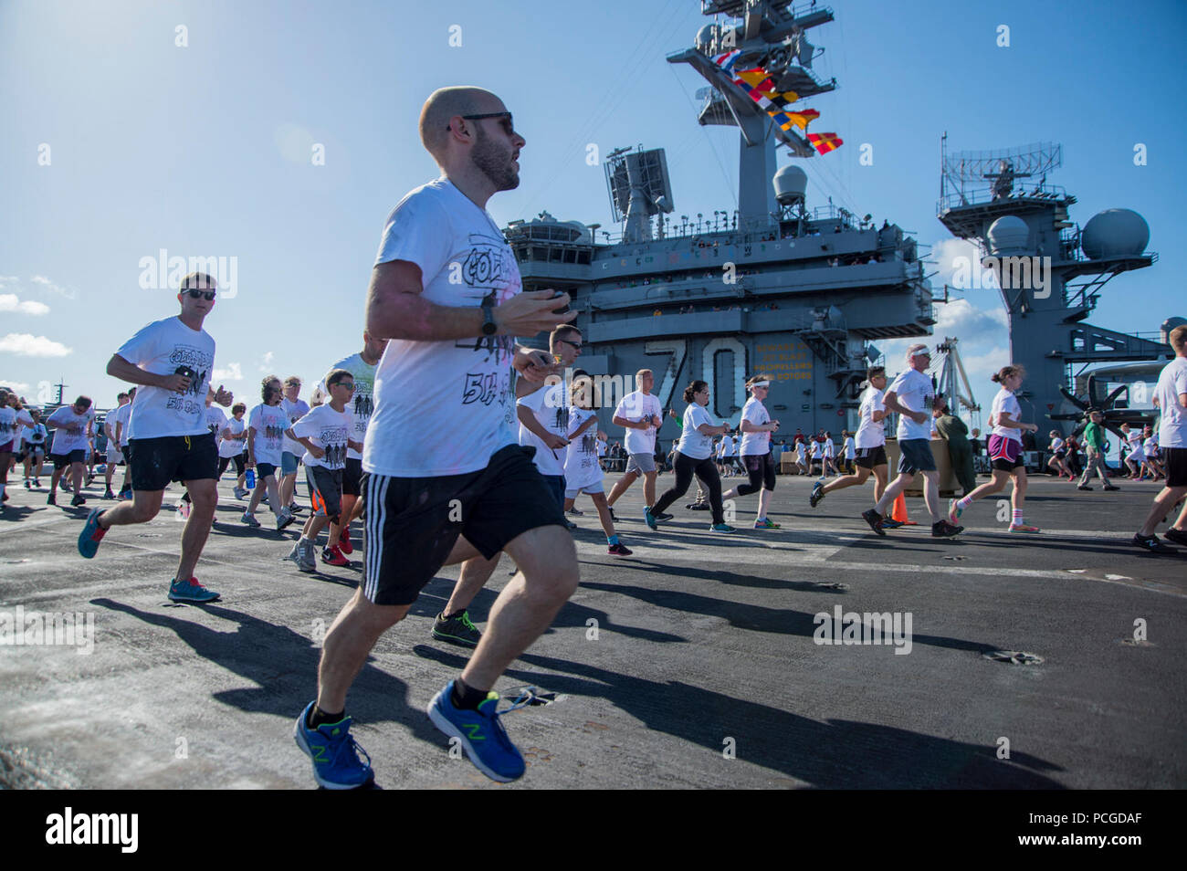 PACIFIC OCEAN (June 1, 2015) Sailors and tiger cruise participants run in the “Color Me Bad” 5 kilometer run aboard the aircraft carrier USS Carl Vinson (CVN 70). Carl Vinson and its embarked air wing, Carrier Air Wing (CVW) 17, are in the U.S. 3rd Fleet area of operations returning to homeport after a Middle East and western Pacific deployment. Stock Photo