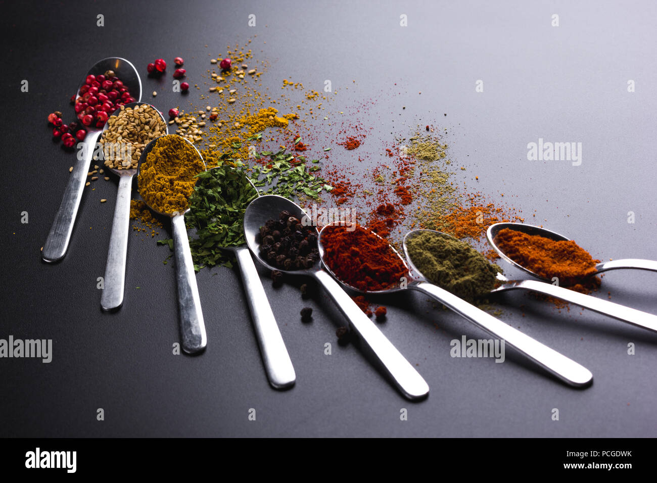Composition of small spoons full of spices and condiments for cooking on a black background Stock Photo