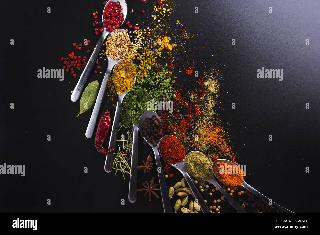 Composition of small spoons full of spices and condiments for cooking on a  black background Stock Photo