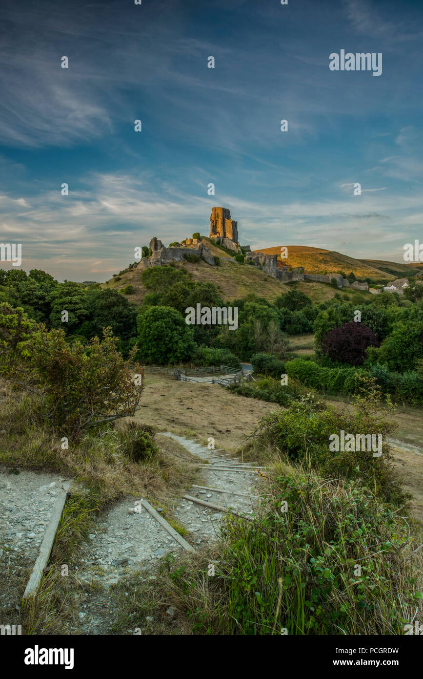 Corfe Castle in Dorset on a summer evening, lite up by the setting sun. Stock Photo