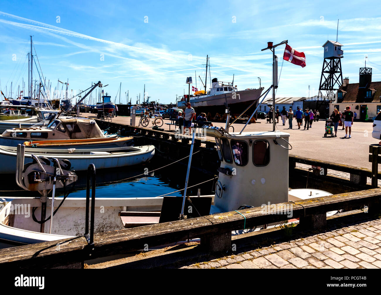 Tourists enjoy a fine day exploring the harbour at Dragør fishing ...
