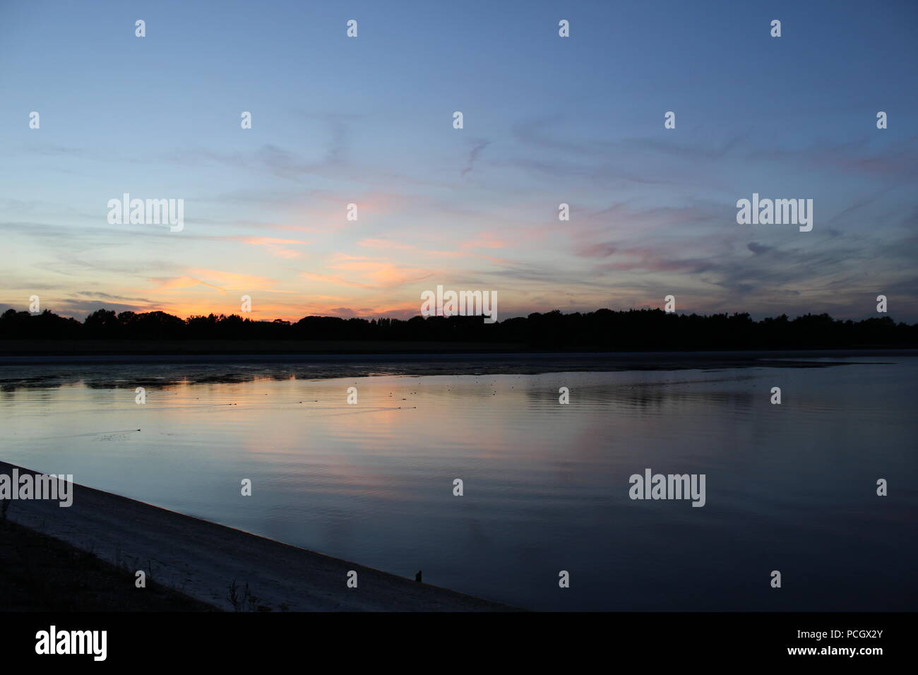 Sunset over ducks swimming on depleted reservoir Stock Photo
