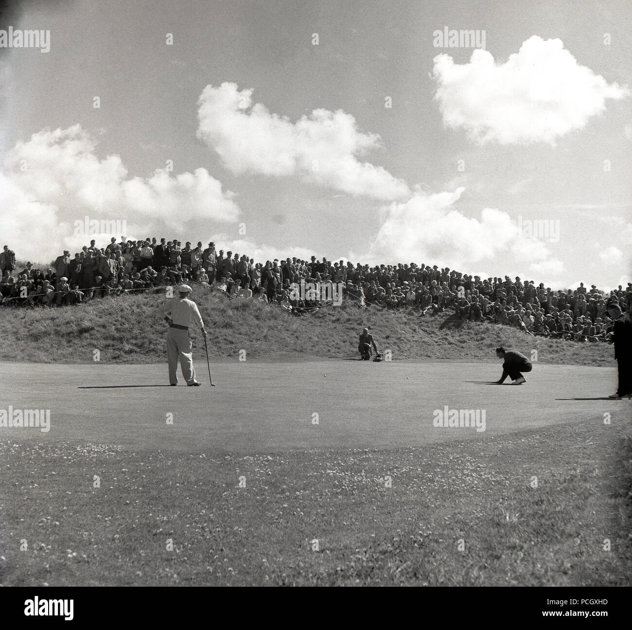 1951, players on a green watched by specators on a sandhill at The Open Championship on the links golf course of Royal Portrush, Co Antrim, Northern Ireland. The event, won by Englishman Max Faulkner who won £300, was often referred to in this era as the 'British Open'. Stock Photo