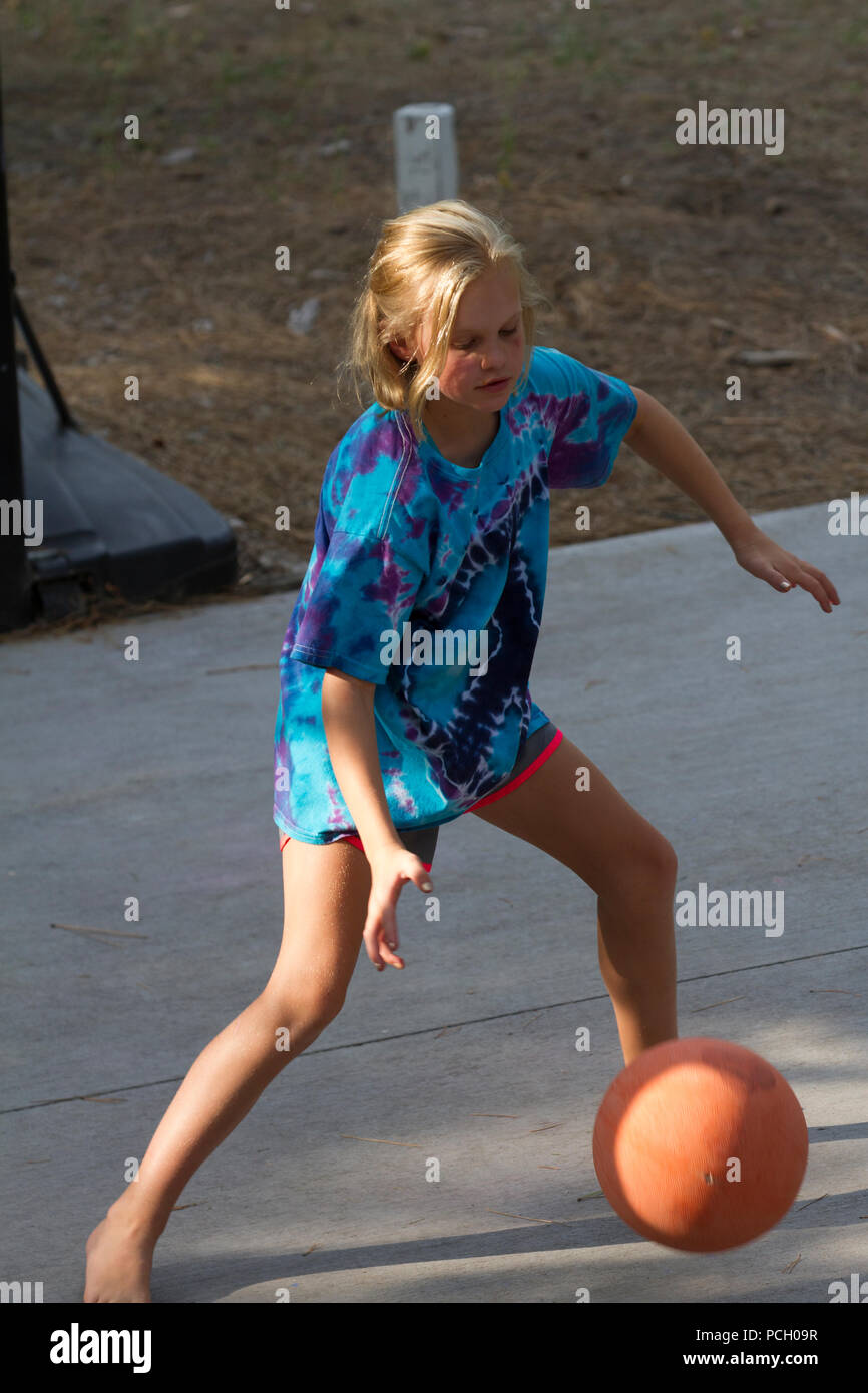 Pretty 8  year old female playing outdoor. basketball, wearing t-shirt and shorts. Model Relese #113 Stock Photo