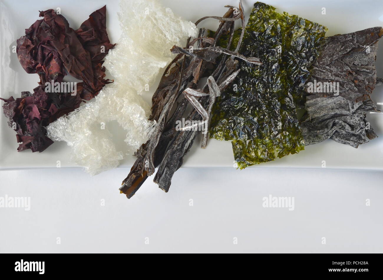 Detail top view of dried seaweed: nori, dulse, kelp, wakame, agar agar, alaria. Isolated on white.Nutrient rich vegan, raw and healthy sea vegetables. Stock Photo