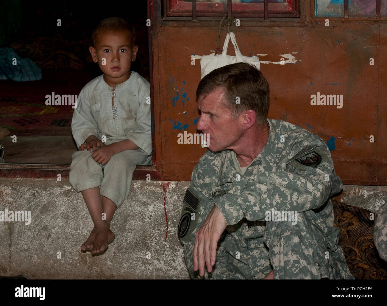 An Afghan boy observes a meeting between U.S. Army Gen. Stanley A. McChrystal, commander of NATO's International Security Assistance Force and U.S. Forces-Afghanistan, and village elders. Stock Photo