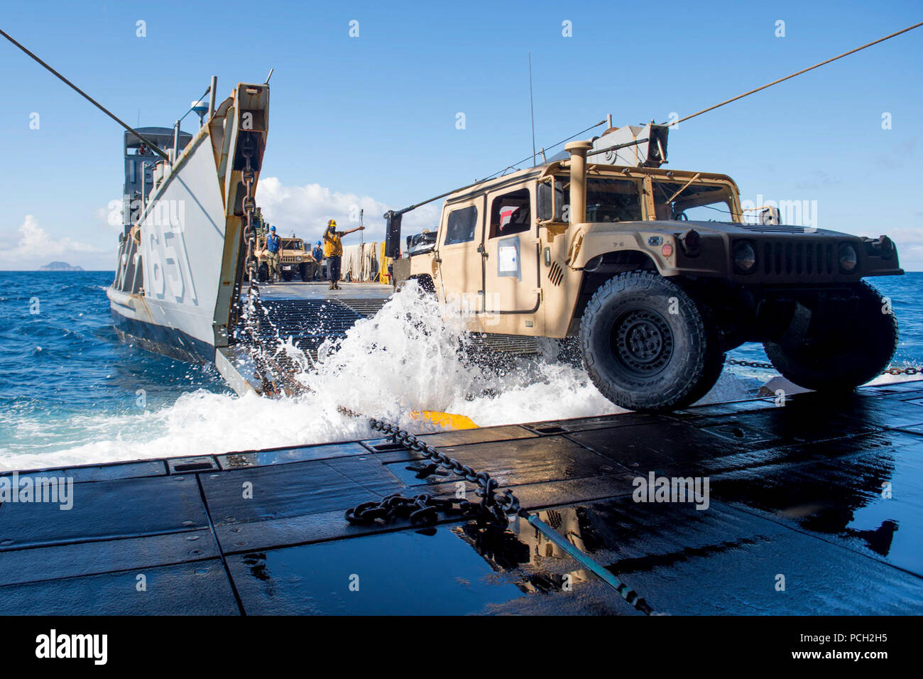 CORAL SEA (July 19, 2017) Boatswain’s Mate 3rd Class Sirus Woodard directs a Humvee onto Landing Craft Utility (LCU) 1651 from the amphibious transport dock ship USS Ashland (LSD 48) as part of an amphibious assault during Talisman Saber 17. Talisman Saber is a biennial U.S.-Australia bilateral exercise held off the coast of Australia meant to achieve interoperability and strengthen the U.S.-Australia alliance. Stock Photo