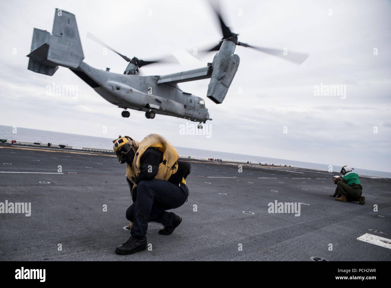 EAST CHINA SEA (March 16, 2017) Aviation Boatswain’s Mate (Handling) 3rd Class Jesse Harris, assigned to amphibious assault ship USS Bonhomme Richard (LHD 6), braces himself as an MV-22B Osprey, assigned to the “Flying Tigers” of Marine Medium Tiltrotor Squadron (VMM) 262, takes off during an air assault exercise. Bonhomme Richard is on a routine patrol operating in the Indo-Asia-Pacific region to enhance warfighting readiness and posture forward as a ready-response force for any type of contingency. Stock Photo