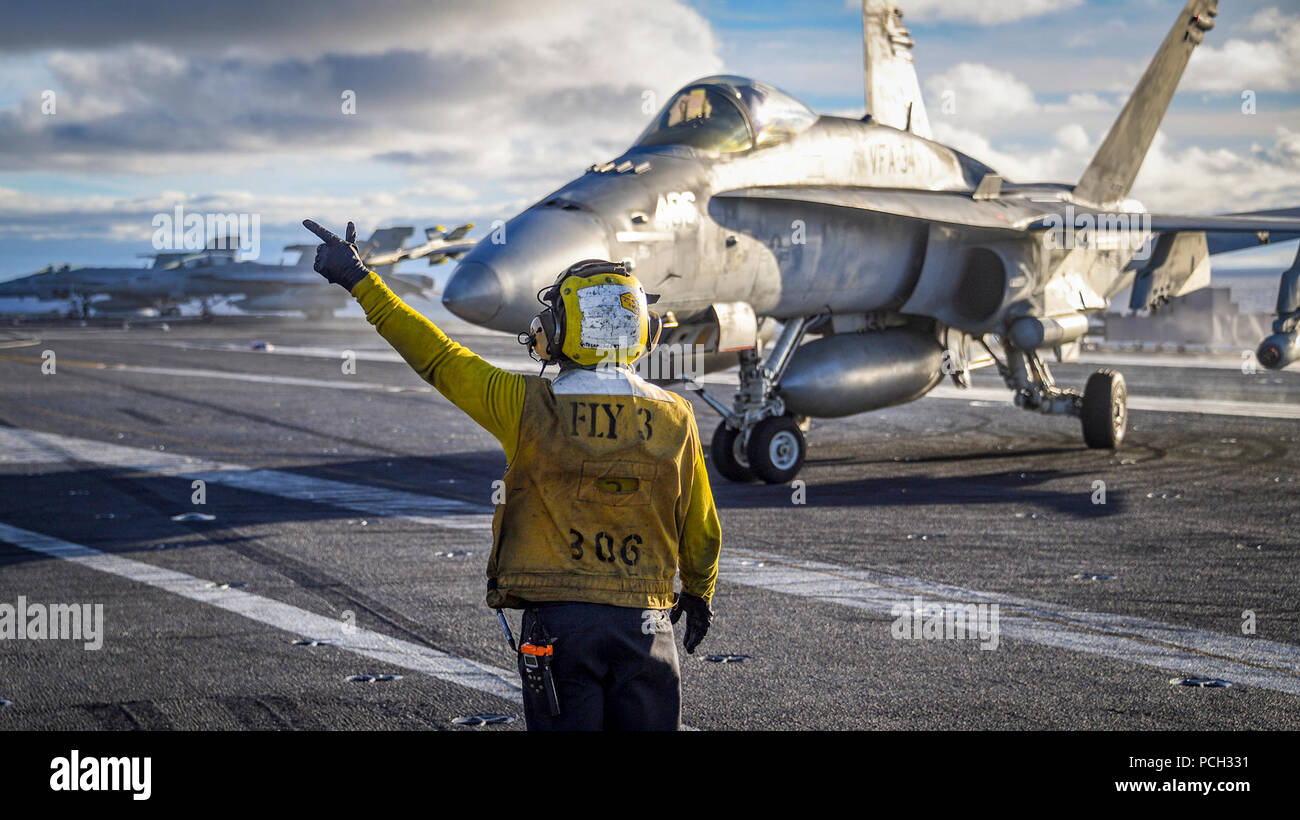 PACIFIC OCEAN (Nov. 9, 2017) Aviation Boatswain’s Mate (Handling) 3rd Class Vincent Sanchez directs the pilot of an F/A-18C Hornet from the “Blue Blasters” of Strike Fighter Squadron (VFA) 34 on the Nimitz-class aircraft carrier USS Carl Vinson (CVN 70) flight deck. Carl Vinson is participating in a sustainment training exercise in preparation for an upcoming deployment. Stock Photo