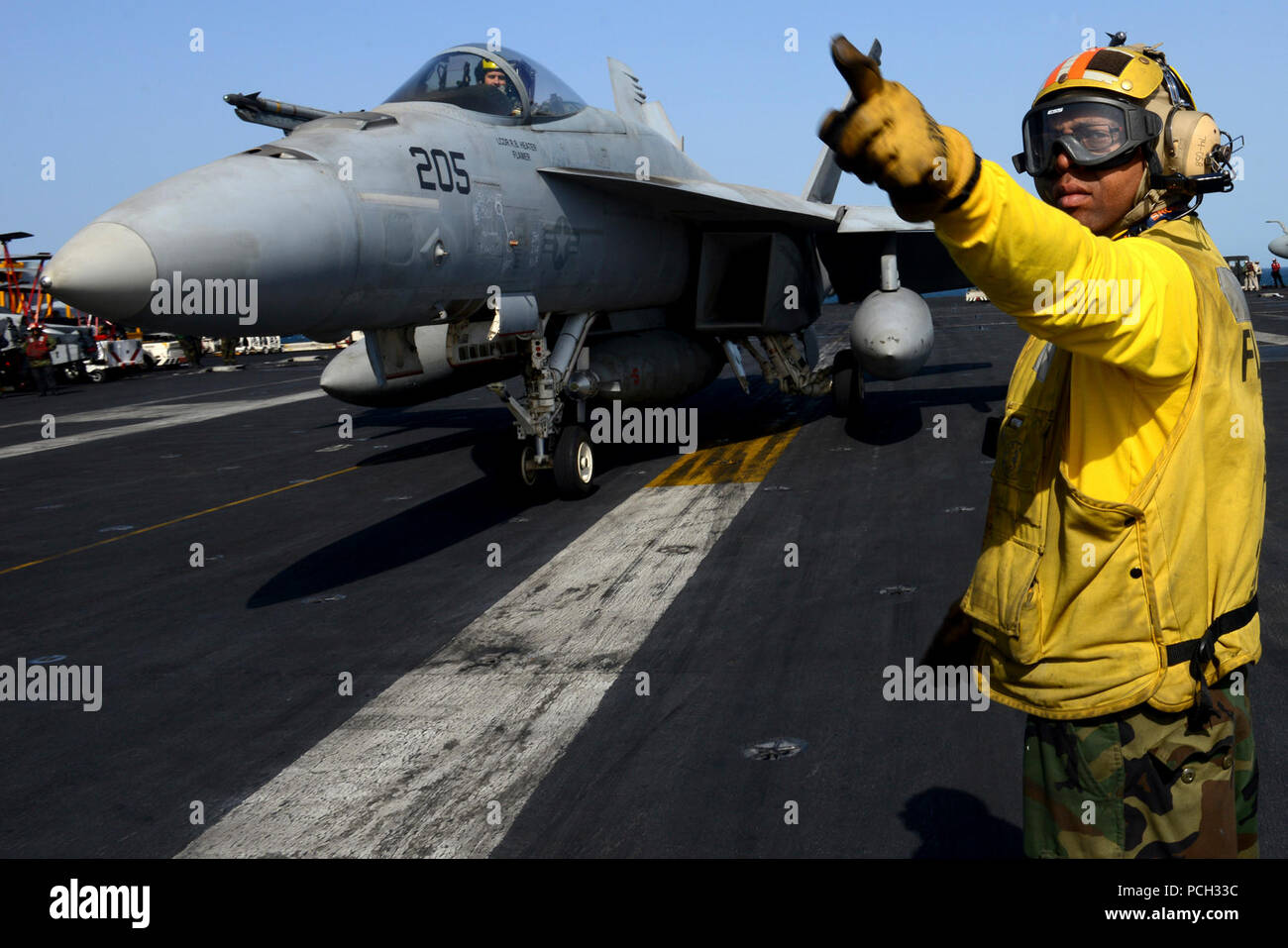 U.S. 5TH FLEET AREA OF RESPONSIBILITY (Jan. 14, 2013) Aviation Boatswain's Mate (Handling) 1st Class Brian Adams, from New York, directs an F/A-18E Super Hornet from the Tophatters of Strike Fighter Squadron (VFA) 14 aboard the aircraft carrier USS John C. Stennis (CVN 74). John C. Stennis is deployed to the U.S. 5th Fleet area of responsibility conducting maritime security operations, theater security cooperation efforts and support missions for Operation Enduring Freedom. Stock Photo