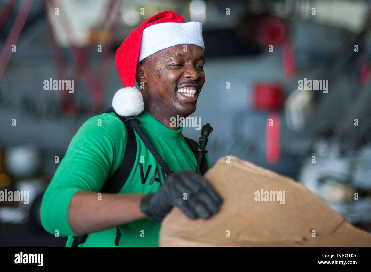 ARABIAN GULF (Dec. 20, 2013) Logistics Specialist 3rd Class Antony Muiruri, from Las Vegas, assigned to the Seahawks of Airborne Early Warning Squadron (VAW) 126, handles packages in the hangar bay of the aircraft carrier USS Harry S. Truman (CVN 75) during a replenishment-at-sea. Harry S. Truman, flagship for the Harry S. Truman Carrier Strike Group, is deployed to the U.S. 5th Fleet area of responsibility conducting maritime security operations, supporting theater security cooperation efforts and supporting Operation Enduring Freedom. Stock Photo