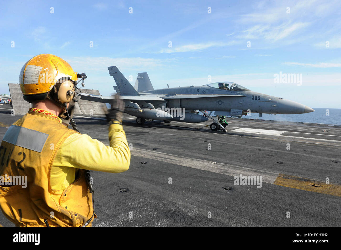 NORTH ARABIAN SEA (April 30, 2013) Aviation Boatswain’s Mate (Handling) 3rd Class Evan Yessick uses hand signals to guide an F/A-18C Hornet assigned to the Rampagers of Strike Fighter Squadron (VFA) 83 onto a catapult on the flight deck of the aircraft carrier USS Dwight D. Eisenhower (CVN 69). Dwight D. Eisenhower is deployed to the U.S. 5th Fleet area of responsibility promoting maritime security operations, theater security cooperation efforts and support missions as part of Operation Enduring Freedom. Stock Photo