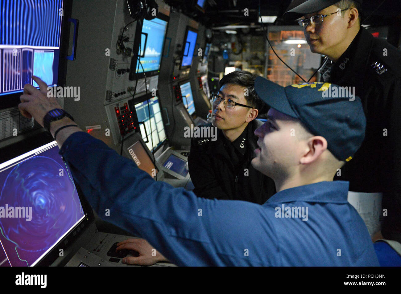 WATERS TO THE WEST OF THE KOREAN PENINSULA (March 16, 2013) Sonar Technician (Surface) 1st Class Andrew Murphy works with Republic of Korea Navy line officers in the sonar control room of the guided-missile destroyer USS McCampbell (DDG 85) during an anti-submarine warfare exercise. McCampbell is part of Destroyer Squadron 15, forward deployed to Yokosuka, Japan, and is underway to conduct exercise Foal Eagle 2013 with the Republic of Korea in support of regional security and stability of the Asia-Pacific region. Stock Photo