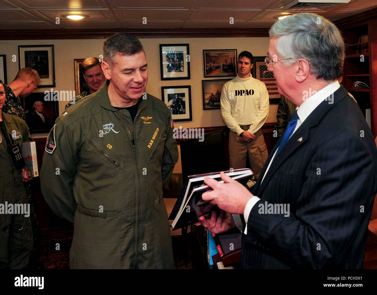 ATLANTIC OCEAN (March 22, 2015) Commanding Officer of the Nimitz-class aircraft carrier USS Theodore Roosevelt (CVN 71) Capt. Daniel Grieco, left, receives a token of appreciation from the United Kingdom Secretary of State for Defence Michael Fallon aboard Theodore Roosevelt March 22, 2015. Theodore Roosevelt, homeported in Norfok, is conducting naval operations in the U.S. 6th Fleet area of operations in support of U.S. national security interests in Europe. Stock Photo