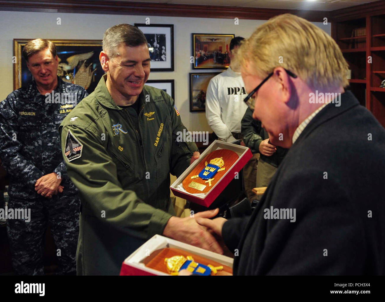 ATLANTIC OCEAN (March 22, 2015) Commanding Officer of the Nimitz-class aircraft carrier USS Theodore Roosevelt (CVN 71) Capt. Daniel Grieco, left, receives a token of appreciation from the Swedish Minister of Defence Peter Hultqvist aboard Theodore Roosevelt March 22, 2015. Theodore Roosevelt, homeported in Norfolk, is conducting naval operations in the U.S. 6th Fleet area of operations in support of U.S. national security interests in Europe. Stock Photo
