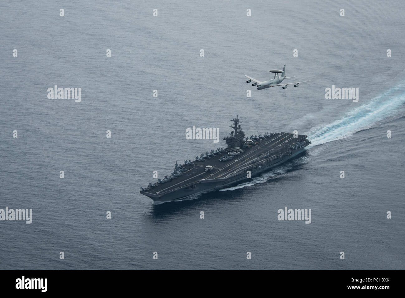 PACIFIC OCEAN (Aug. 21, 2017) A U.S. Air Force E-3 Sentry airborne warning and control system assigned to Air Combat Command at Tinker Air Force Base flies over the aircraft carrier USS Theodore Roosevelt (CVN 71). Theodore Roosevelt is underway conducting a composite training unit exercise (COMPTUEX) with its carrier strike group in preparation for an upcoming deployment. COMPTUEX tests a carrier strike group’s mission-readiness and ability to perform as an integrated unit through simulated real-world scenarios. Stock Photo