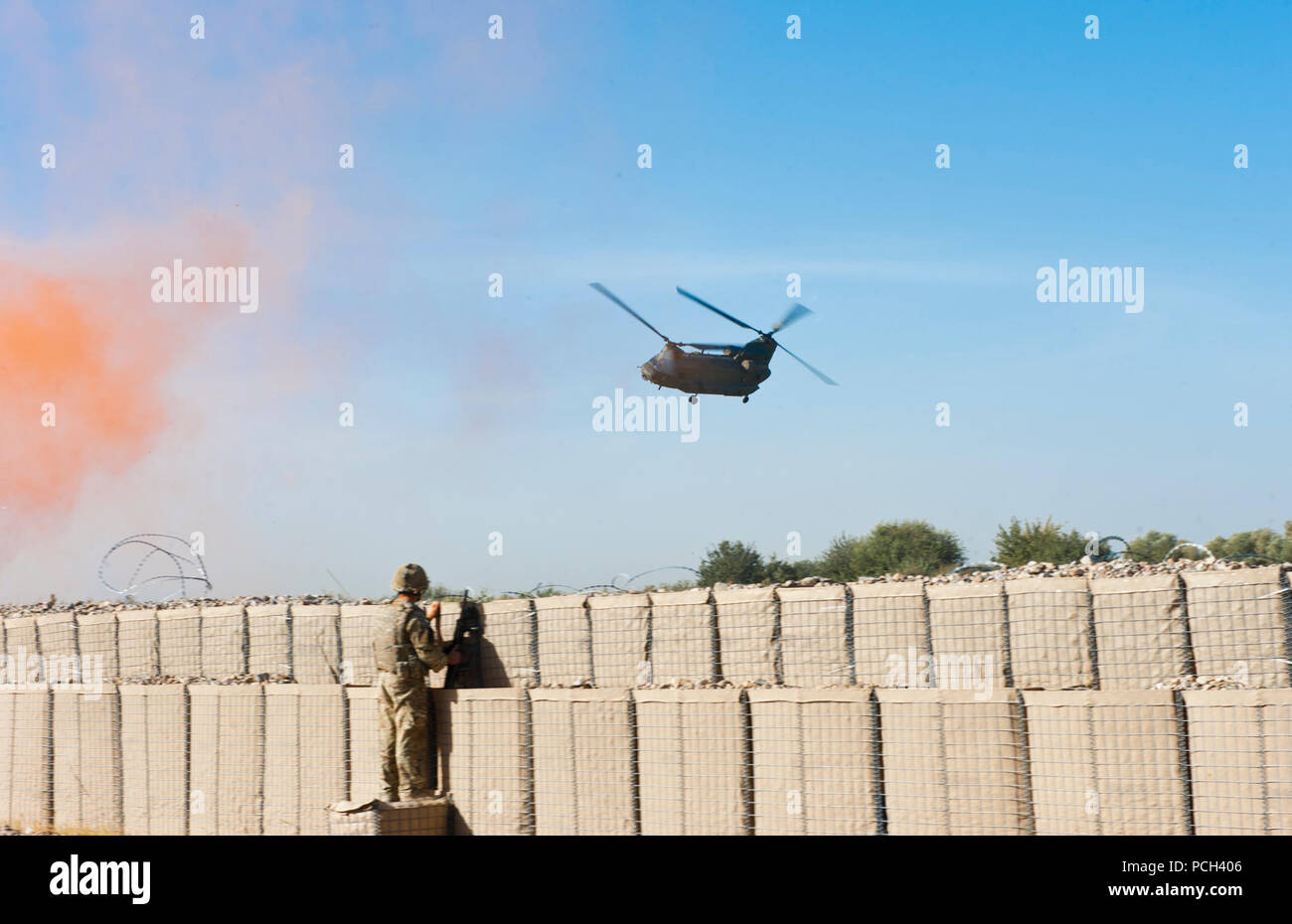 A U.S. Marine watches as a Royal Air Force CH-47 Chinook helicopter turns while preparing to land at Patrolling Base Jaker in Nahr-e Saraj district, Helmand province, Sept. 13, 2011. Stock Photo