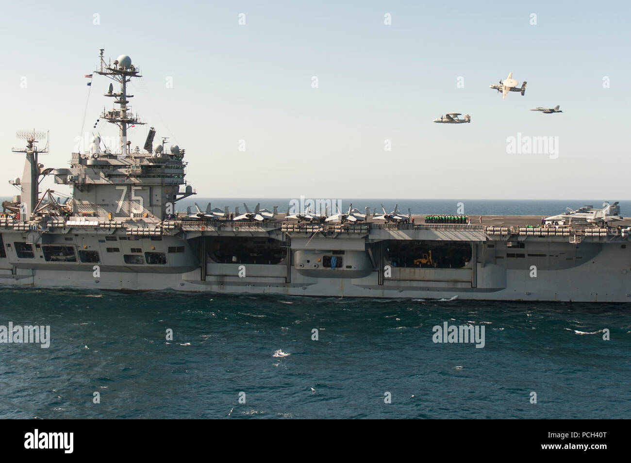 A U.S. Navy E-2C Hawkeye aircraft flown by Cmdr. John Hewitt, top, the outgoing commanding officer of Carrier Airborne Early Warning Squadron (VAW) 126, an E-2C flown by Cmdr. Przemyslaw Kaczynski, left, the squadron's incoming commanding officer, and an EA-18G Growler aircraft flown by Capt. George Wikoff, the commander of Carrier Air Wing (CVW) 3, participate in an aerial change of command ceremony over the aircraft carrier USS Harry S. Truman (CVN 75) March 18, 2014, in the Gulf of Oman. The Harry S. Truman Carrier Strike Group was deployed to the U.S. 5th Fleet area of responsibility suppo Stock Photo