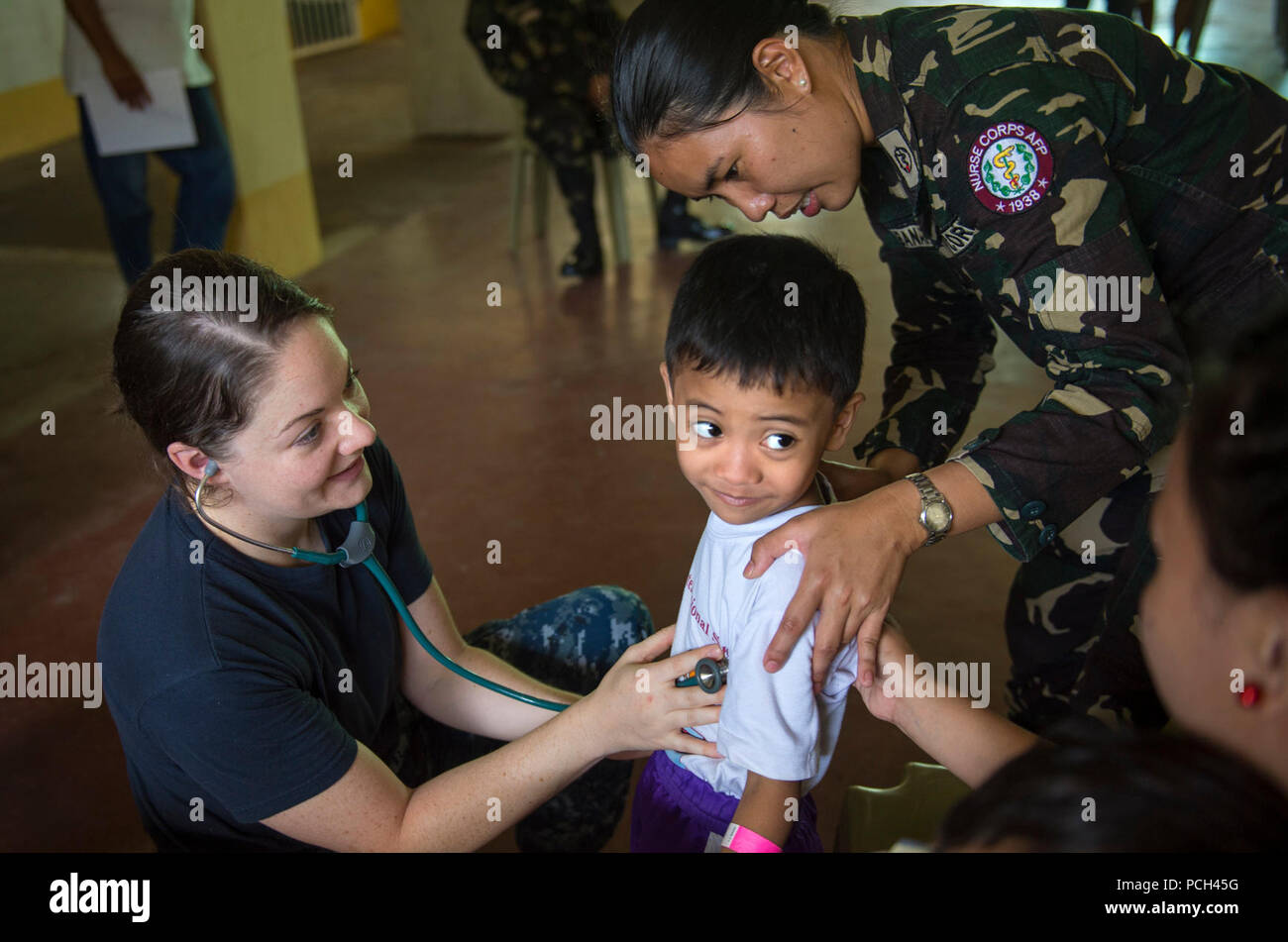 LIGAO CITY, Philippines (June 28, 2016) Lt. Noelle Cadette, a U.S. Navy nurse assigned to the hospital ship USNS Mercy (T-AH 19), left, and 2nd Lt. Irish F. Banaybanay, from the Philippine Nurse Corps, listen to a child's lungs at Ligao West Central Elementary School during Pacific Partnership 2016. Cadette, from Norwalk, Conn., was at the school as part of a cooperative health engagement where Pacific Partnership 2016 personnel attached to Mercy and members of the Armed Forces of the Philippines spent the day educating people on health care, hygiene and nutrition. Participants also provided d Stock Photo